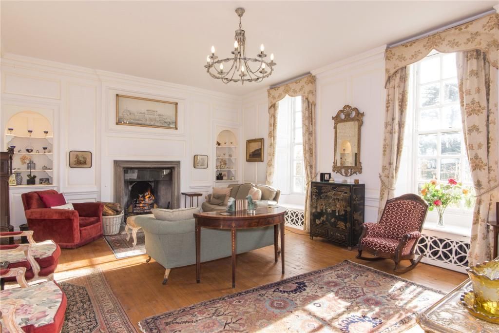 Another living area inside the home with open fireplace and armchairs plus a sideboard and mirror