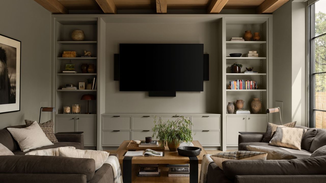 modern living room with tv mounted on wall, two L-shaped sofas facing each other and built-in bookcase with decor