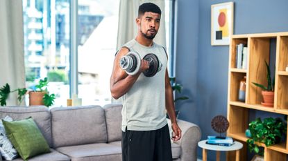 Young man in vest doing a dumbbell workout at home