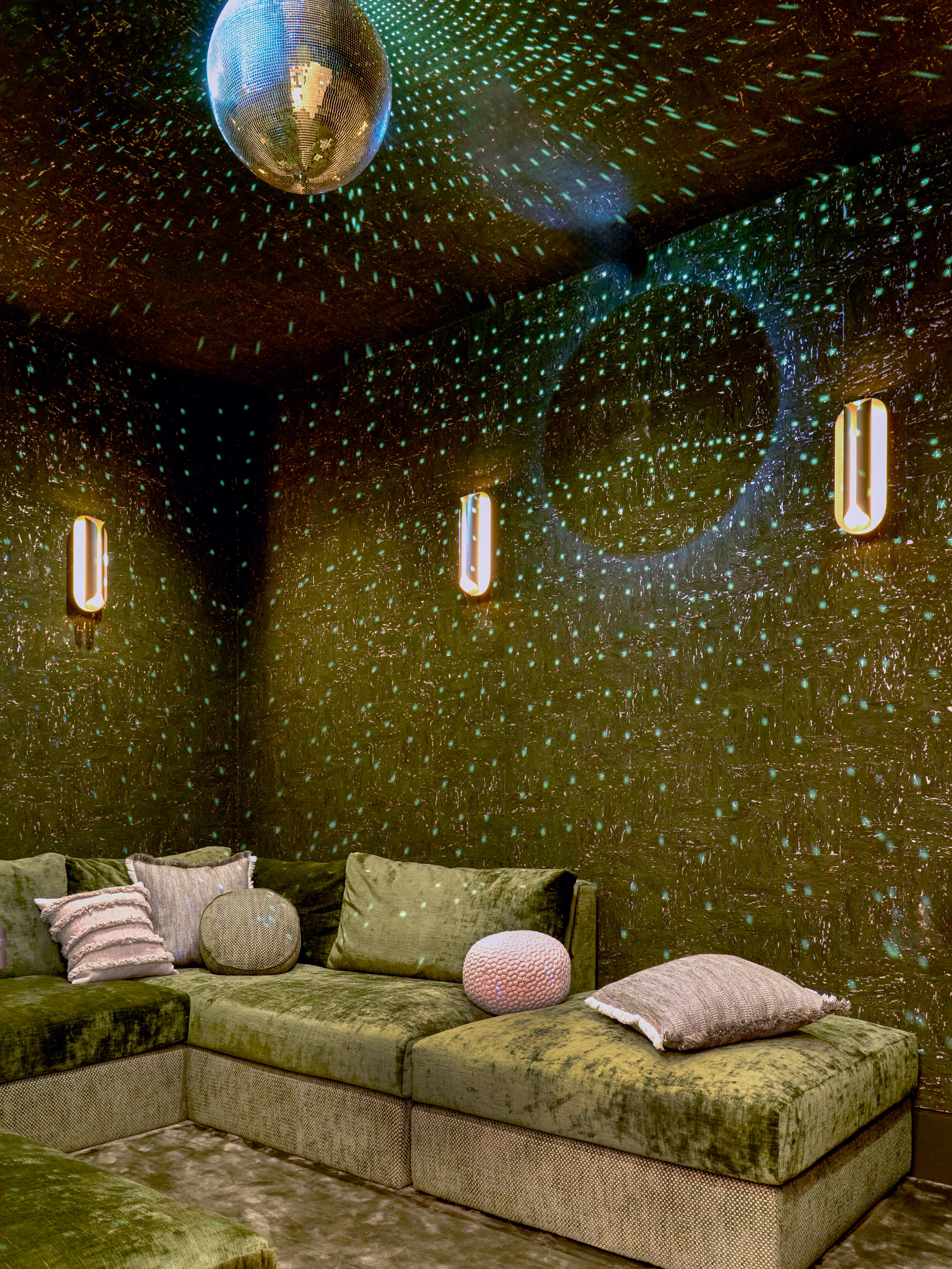 Snug with green walls, green velour built-in sofa and disco ball