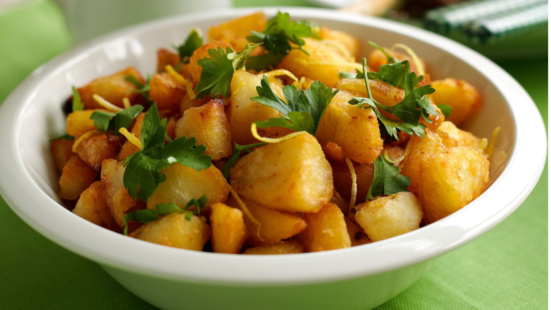 Crispy roast potatoes in a bowl with a sprig of parsley