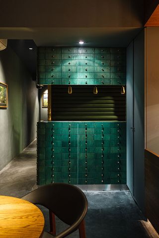 Alternative view of the teal, black and gold dining pod at Cure. The walls are dark grey with framed wall art and there is a wooden dining table and dark coloured chair close by