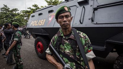Indonesian soldiers stand guard near an Indonesian armored vehicle carrying the convicted Australian smugglers