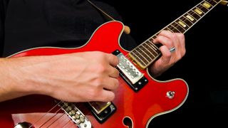 Young guitarist playing red vintage hollow body electric guitar