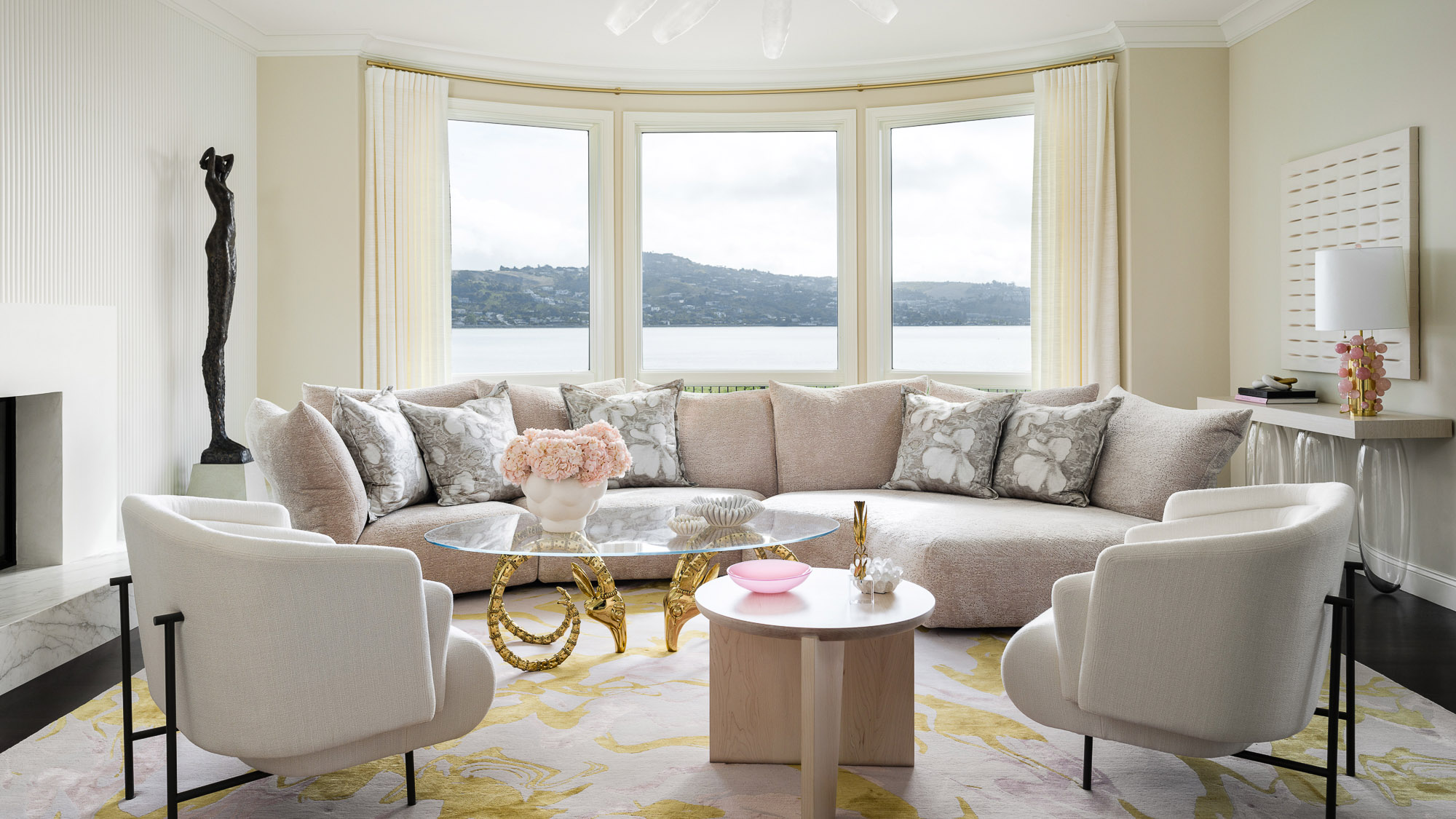 large white living room with white sofa in a bay window and white armchairs
