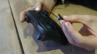 En person håller på att byta ut styrspakarna på en svart Xbox Elite Controller Series 2.
