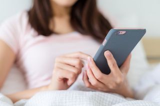 A woman looking at her phone while in bed.