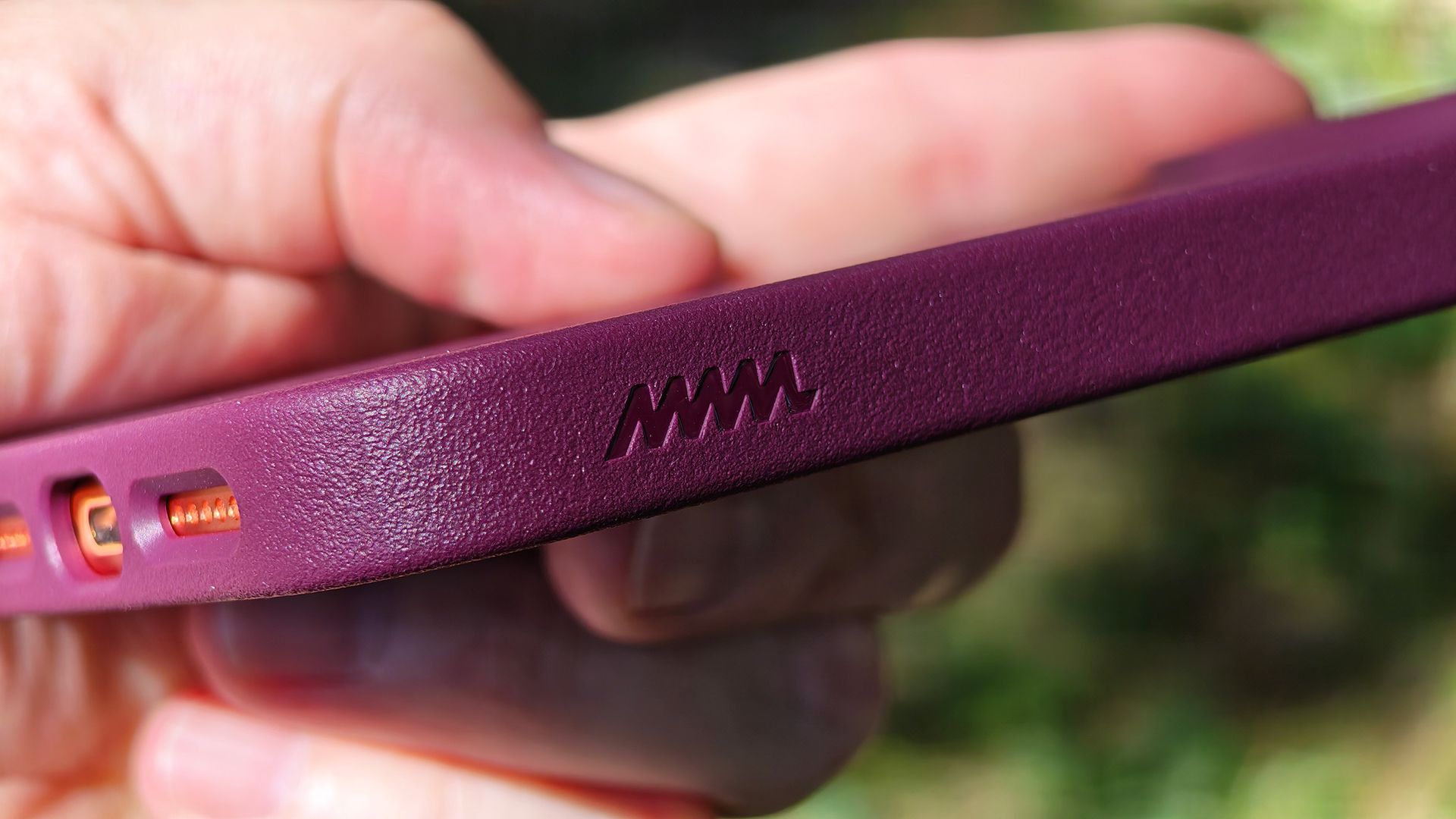 A burgundy Dbrand MNML case on an orange Apple iPhone 17 Pro Max
