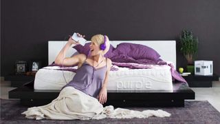 Lady sitting next to Purple mattress listening to music