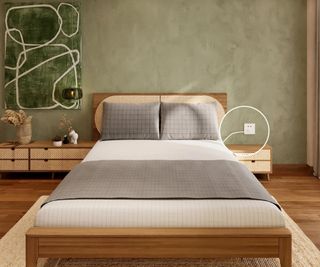 Gray and white grounding sheets on a bed against a light green wall.