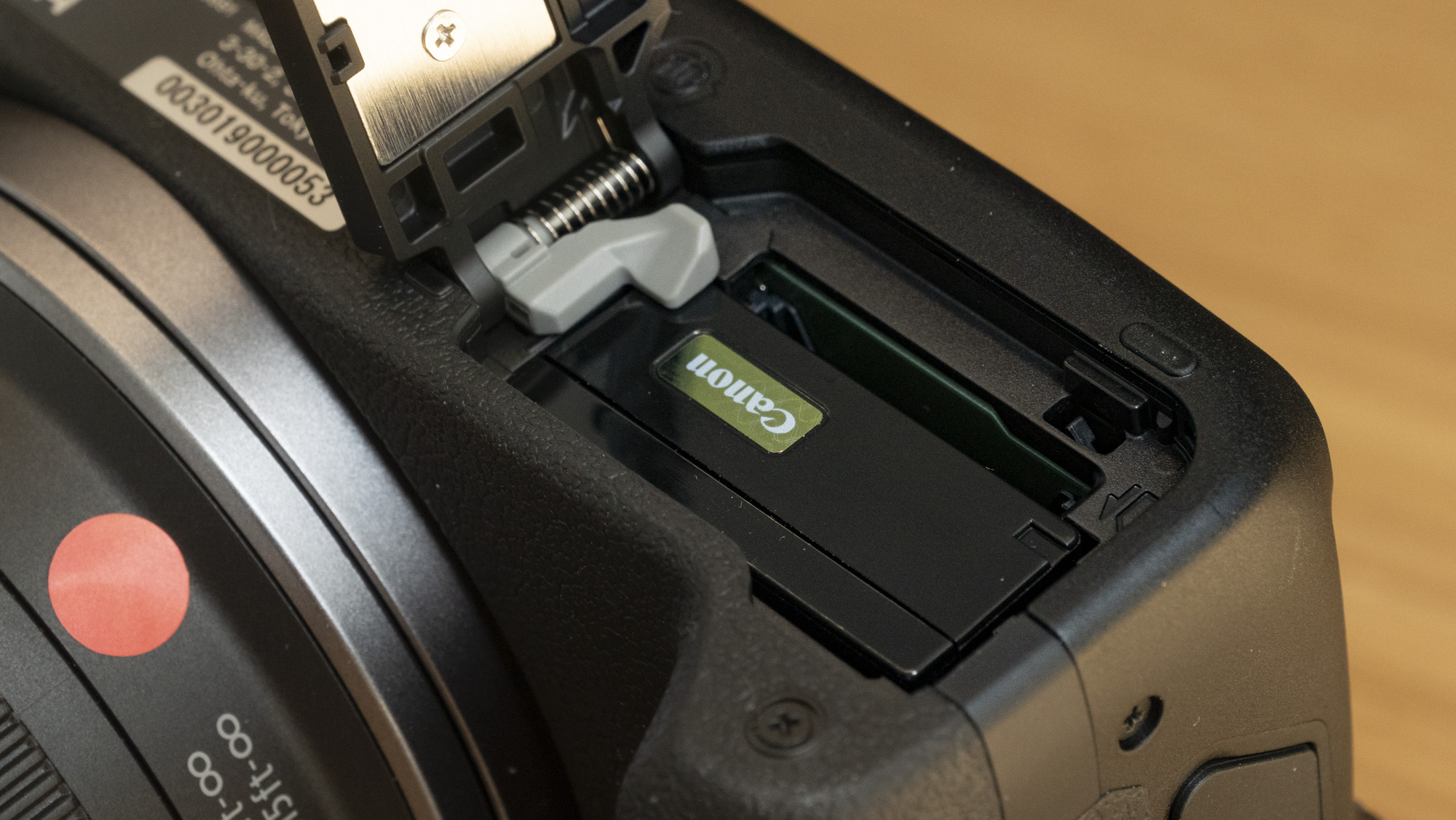 Canon EOS R100 camera on a table closeup of the battery door