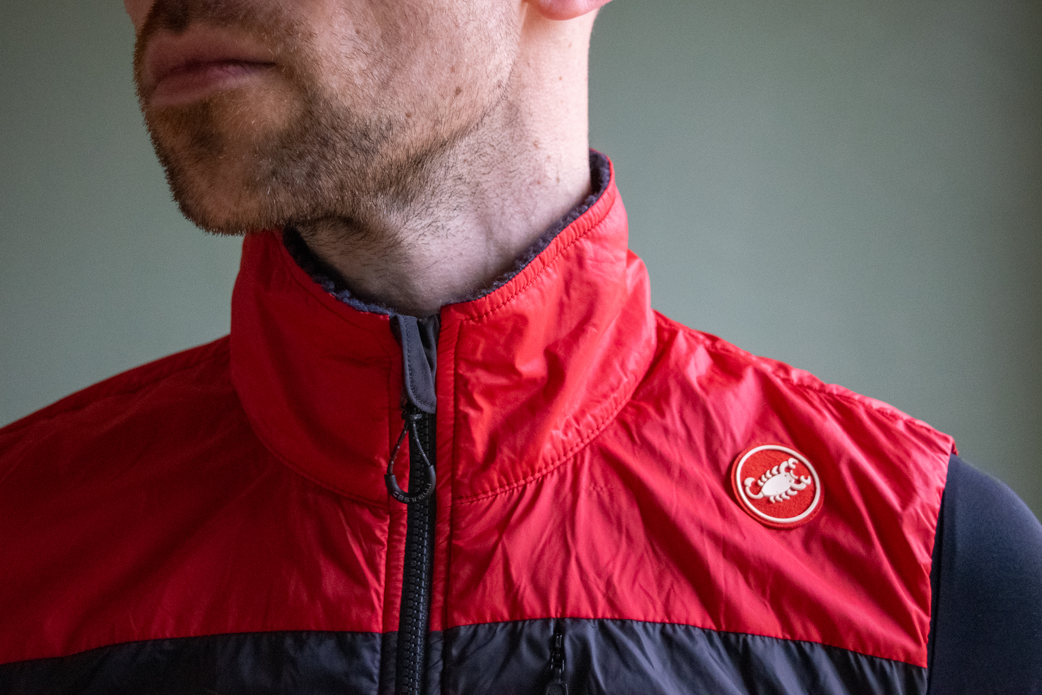 A male cyclist wearing a red Castelli Unlimited Puffy vest