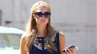 Paris Hilton seen shopping in LA, wearing sunglasses and holding her phones.