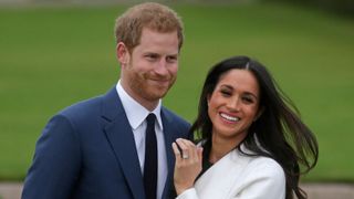 Prince Harry stands with his fiancée Meghan Markle as she shows her engagement ring