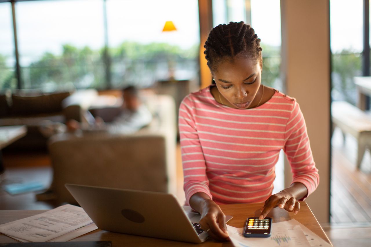 Young woman at desk with laptop and phone