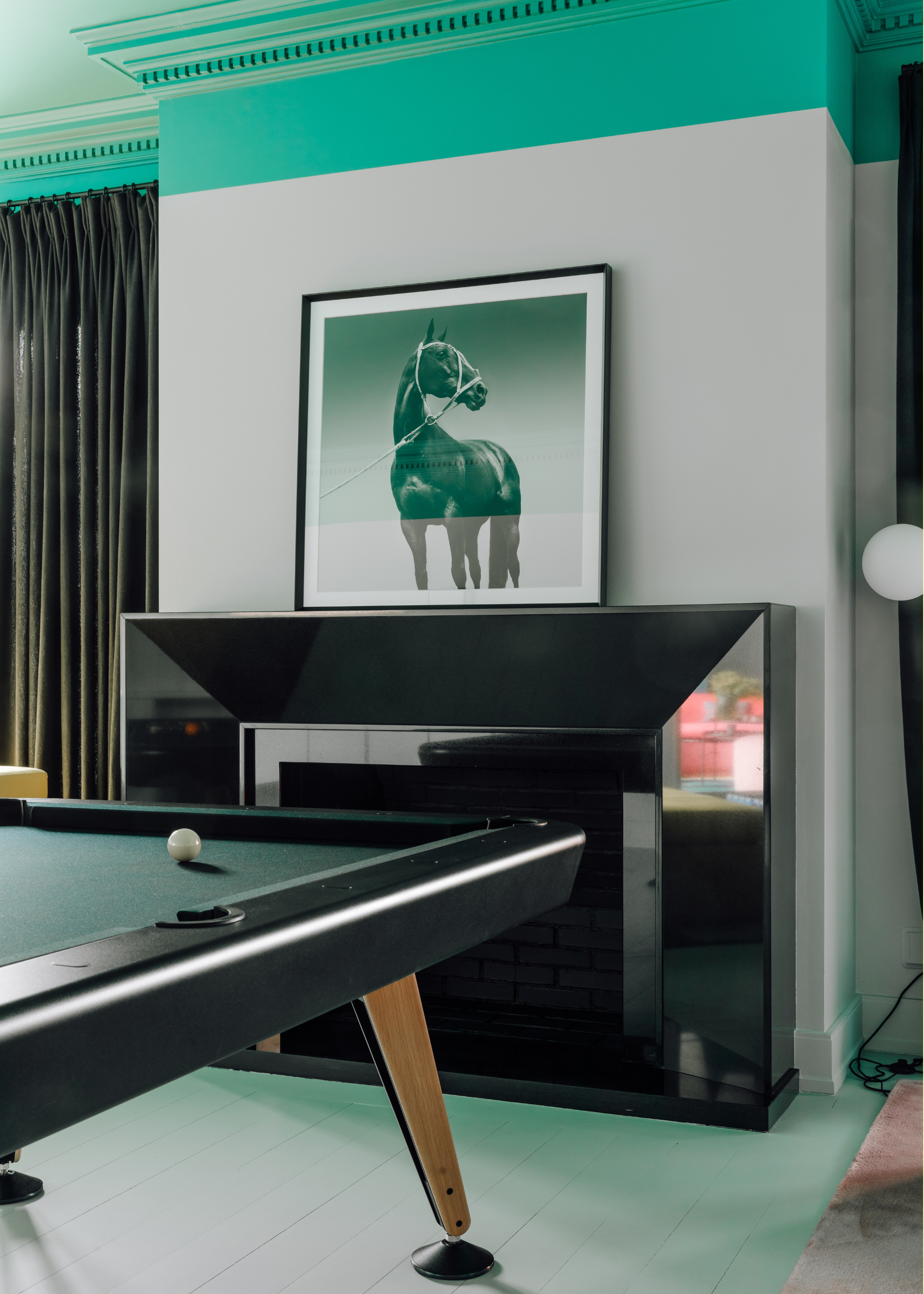 An entertainment room with a black fireplace, a picture of a horse leaning on the mantel and a fluorescent blue trim by the ceiling