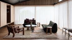 A laid-back living room with earthy brown tones and green accents featuring an area rug, two sofa couches and one arm chair