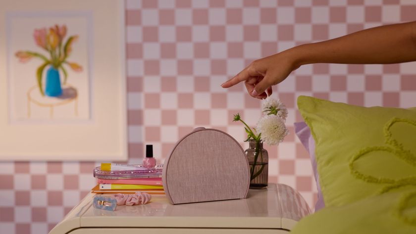 Rosy pink Hatch Restore 3 next to book, hair accessories and plant on bedside table in pink room with check wallpaper and green bedding