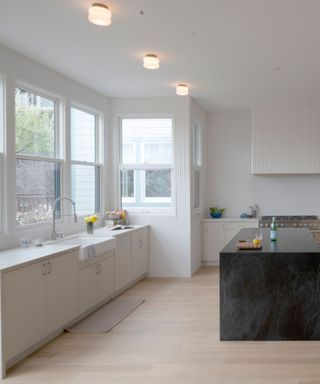 white kitchen with white countertops and cabinets, black kitchen island