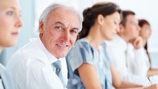 Senior business man sitting with colleagues in a row during meeting