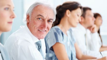 Senior business man sitting with colleagues in a row during meeting