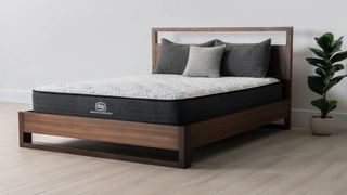 Brooklyn Bedding Essential Mattress on a wooden bedframe, dressed with grey pillows