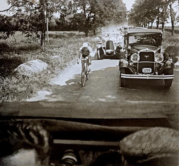 This photo is a unique image from the 1930 Tour, and shows a rider&rsquo;s solo effort. Research has not unearthed who the rider is but the focus on his exploit is evident from the entourage of Tour press vehicles surrounding the competitor.