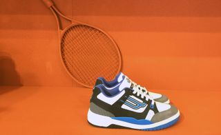 Sneakers stand near an orange tennis racket