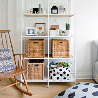 White shelving unit in a white living room, with storage baskets to stash clutter