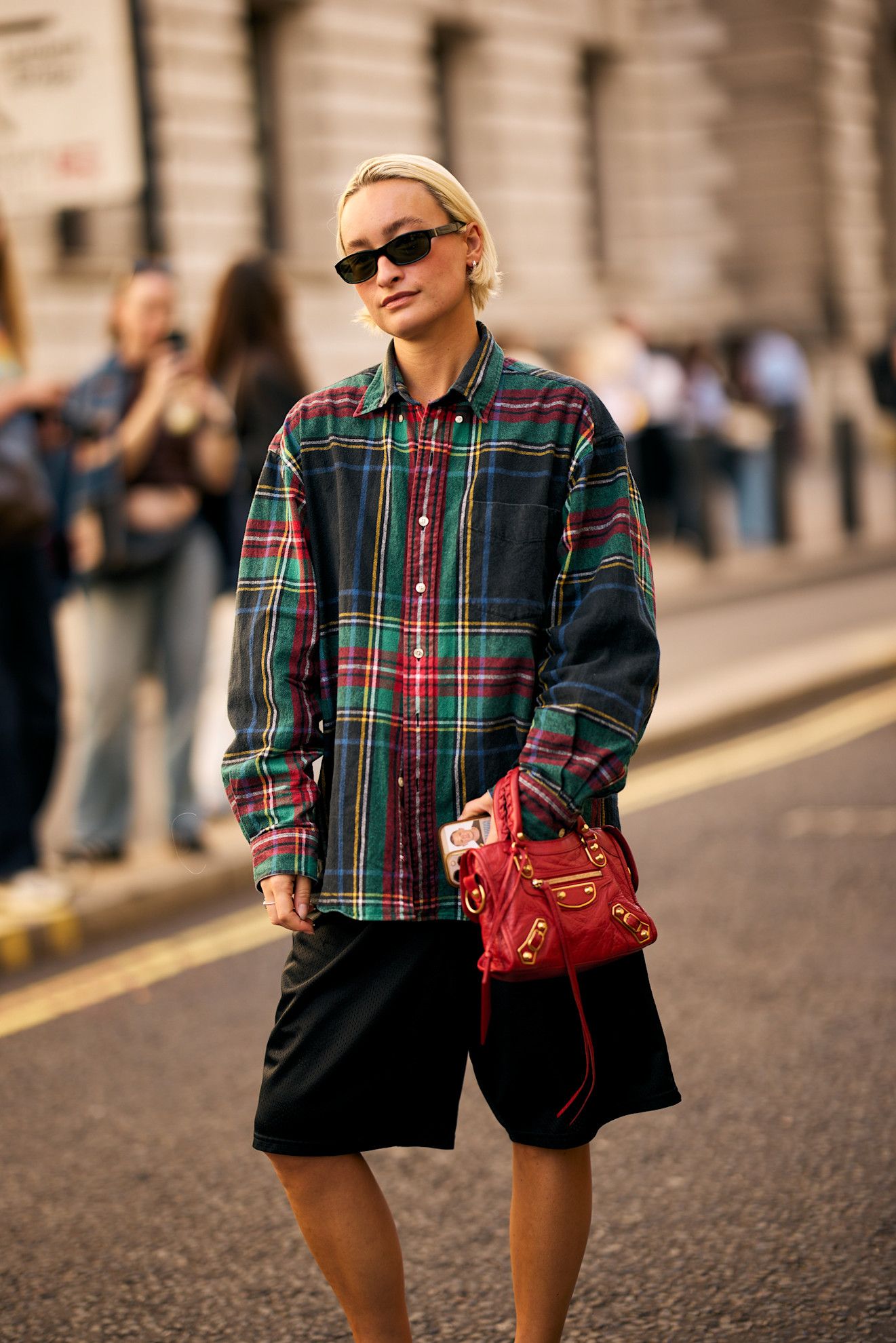 a white woman with a short blonde bob in a plaid shirt and black shorts