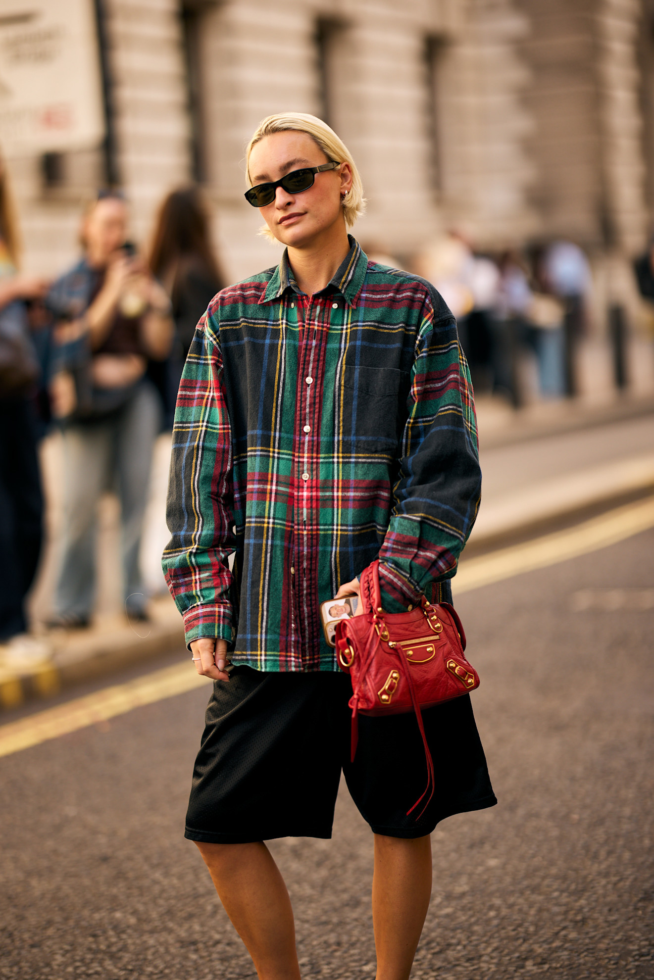 a white woman with a short blonde bob in a plaid shirt and black shorts