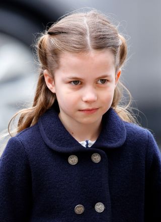 Princess Charlotte wears a navy coat with silver buttons and stares