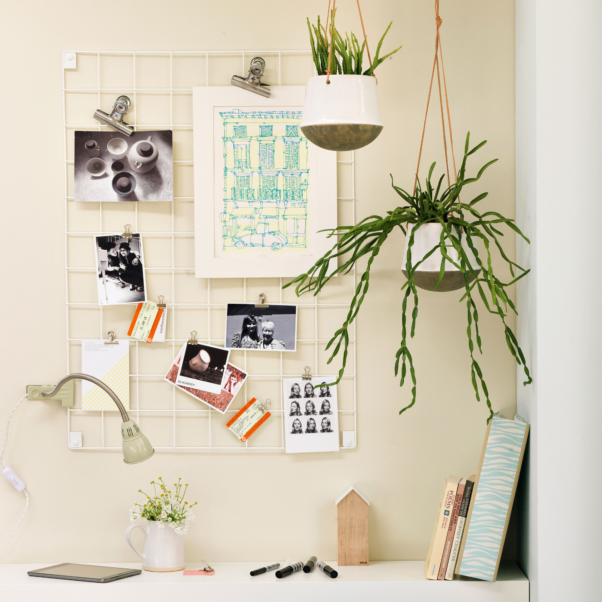 Home office desk setup with wired grid decor displaying photos and artwork