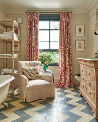 Traditional bathroom with vintage furniture, chevron floor tiles, armchair and floral curtains