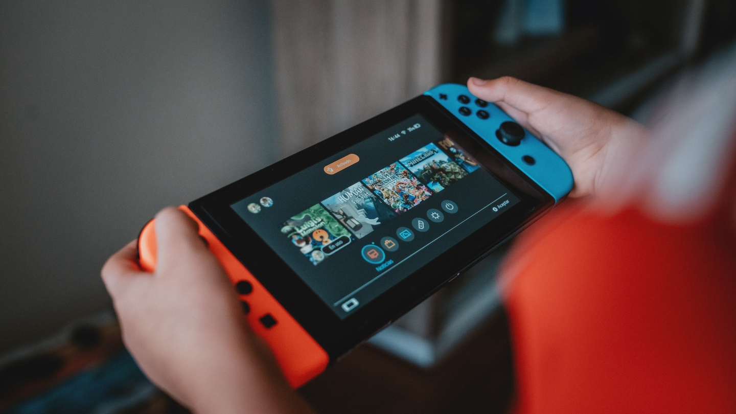 Two hands holding either side of a blue and red Nintendo Switch