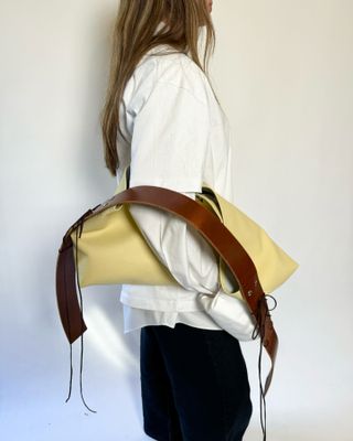 Model holding a yellow bag.