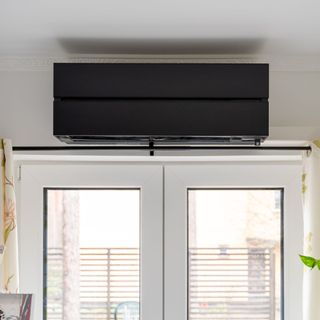 Black internal air source heat pump unit above patio doors