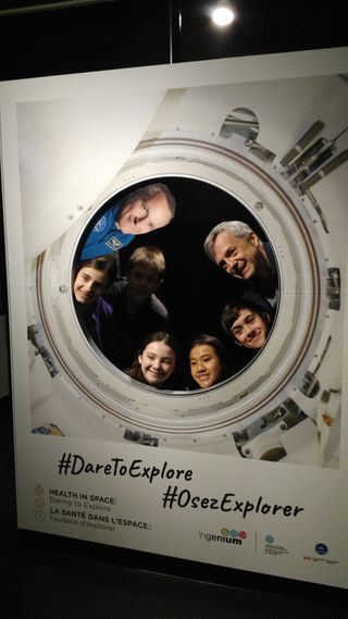 Former Canadian astronaut Robert Thirsk (top right) poses with schoolchildren at a new museum exhibit at the Canada Aviation and Space Museum in Ottawa on Feb. 7, 2019. The exhibit highlights the contributions of medical space technology to astronaut and consumer health. It also features astronaut doctors such as David Saint-Jacques. A flat picture of Saint-Jacques is displayed at top left.