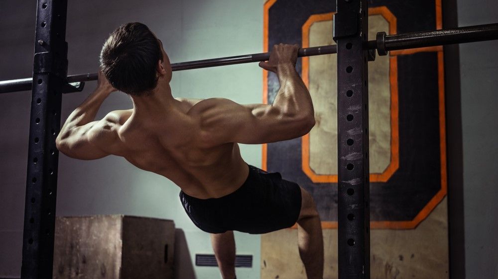 a photo of a man doing an inverted pull up