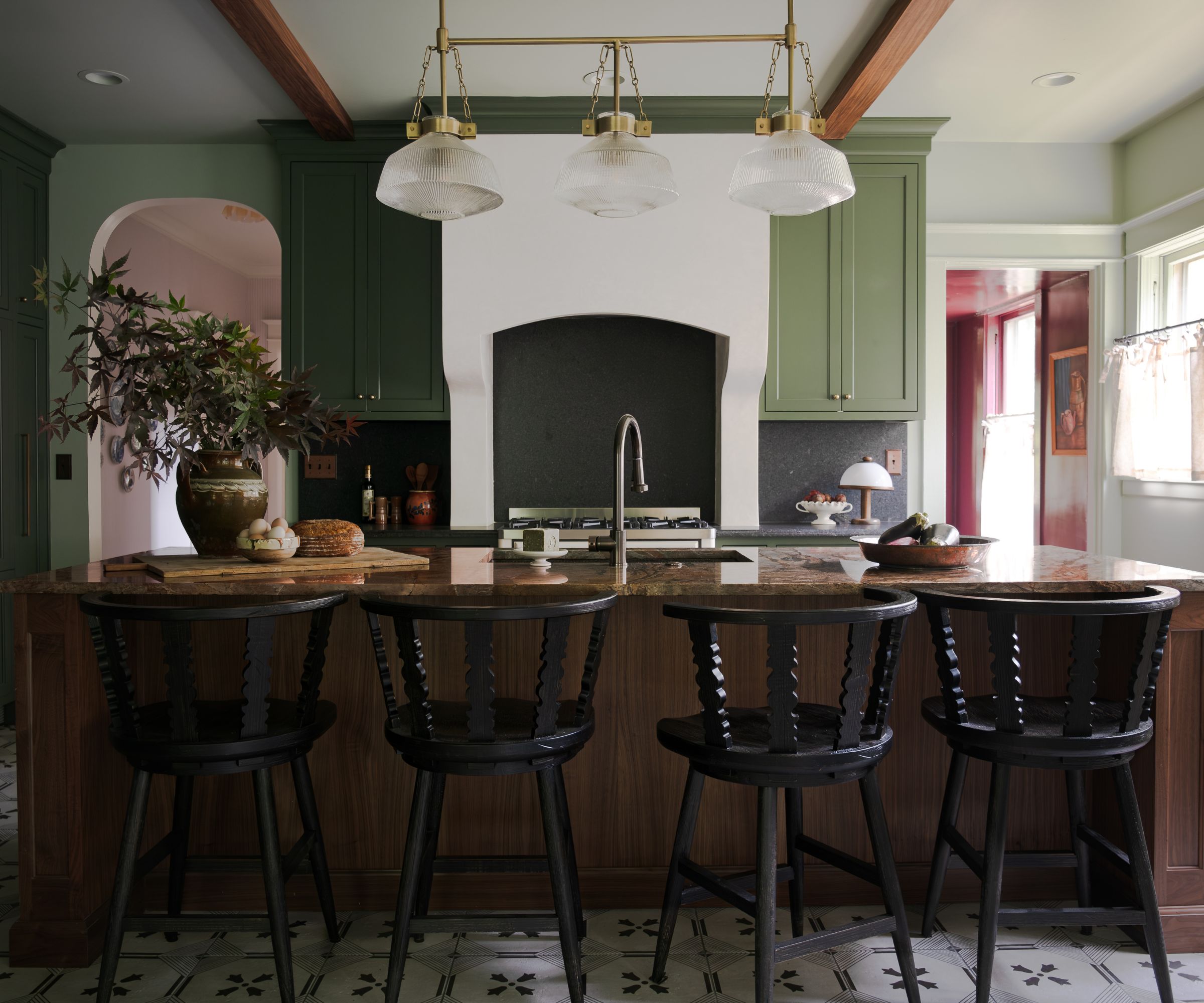 A Craftsman kitchen with dark green shaker cabinets, light green walls and ceiling, and a large dark wood island