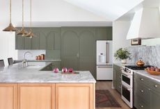 A kitchen with dark green cabinets and white walls