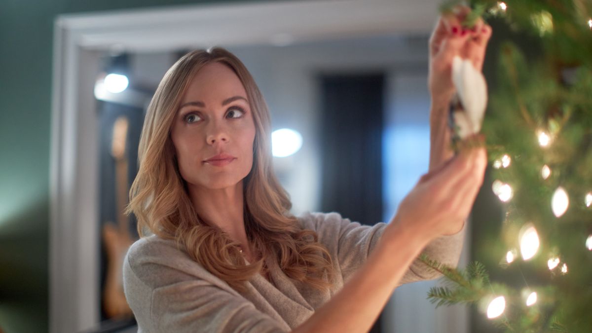 Laura Vandervoort as Mary Ann hangs an ornament on the tree in Miracle in Bethlehem, PA