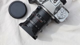 Thypoch Simera 28mm f/1.4 lens attached to a Fujifilm X-T5 camera on a beige cloth