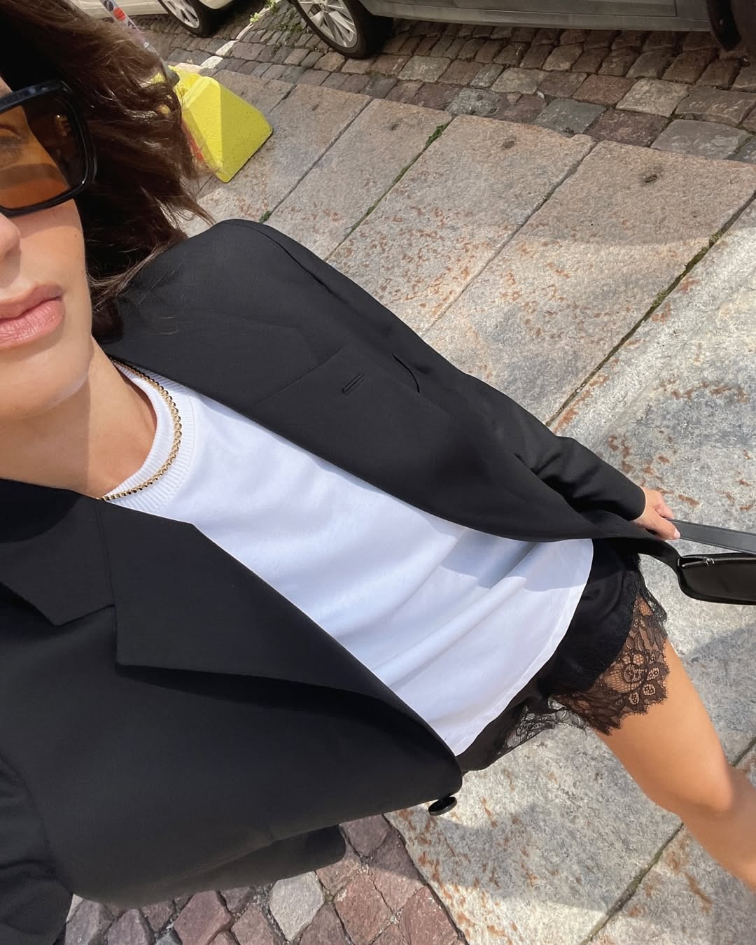 Woman in black blazer, white t-shirt, and black lace skirt.