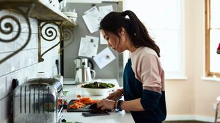 Woman cooking in kitchen at home, chopping carrots