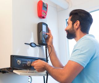 Asian man stood in front of gas boiler running tests