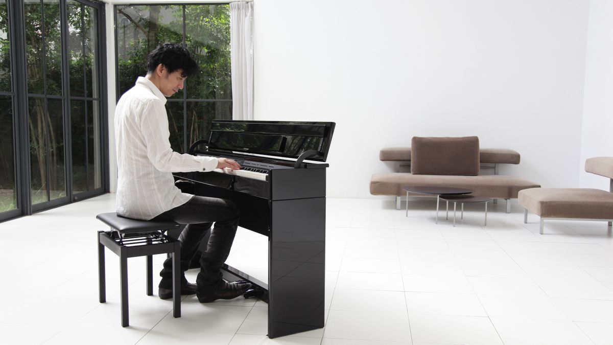 Man sits behind a Roland digital piano in a white room