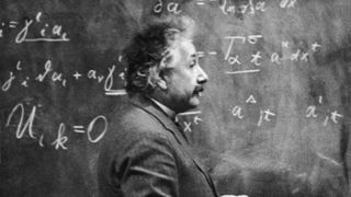 Einstein standing in front of a chalkboard full of equations