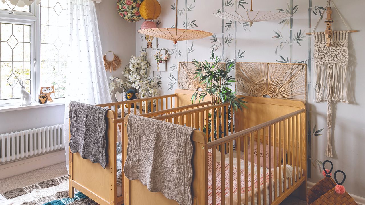 Two wooden cots in front of green and white patterned wall, with cosy rug and blankets