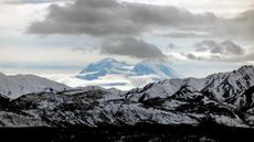 A snowy mountain range under a cloudy sky.